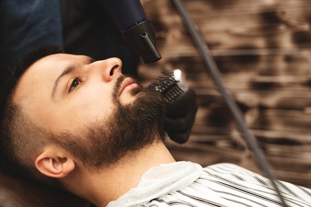 Photo shaving a beard in a barbershop with a dangerous razor. barber shop beard care. drying, cutting, cutting a beard. selective focus.