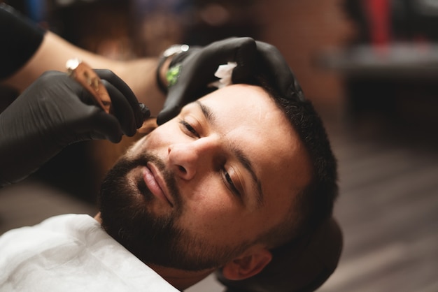 Shaving a beard in a barbershop with a dangerous razor.