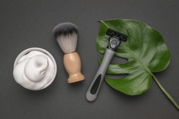 Shaving kit and a large green leaf on a dark background