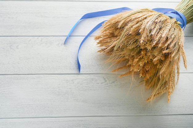 Shavuot jewish holiday celebration Bouquet of golden ripe wheat with a blue ribbon White wood board table with field of wheat Background for Shavuot celebration Top view Mock up