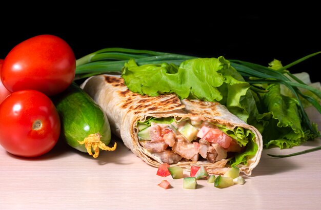 Shawarma appetizing of pita bread fried beef fresh vegetables and cheese on a wooden background