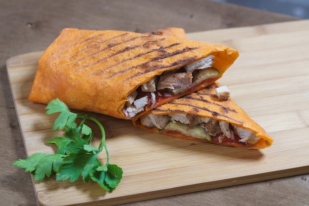 Shawarma chicken roll in a pita on wooden background.