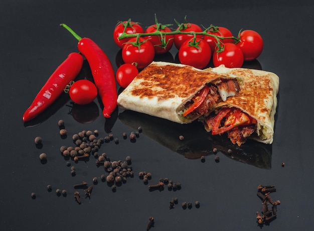 Shawarma cut with chicken meat on black background closeup Cheese red pepper parsley