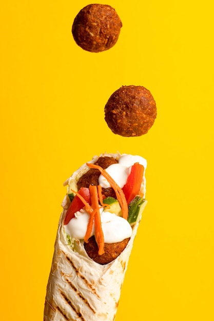 Shawarma with falafel side view on a yellow background