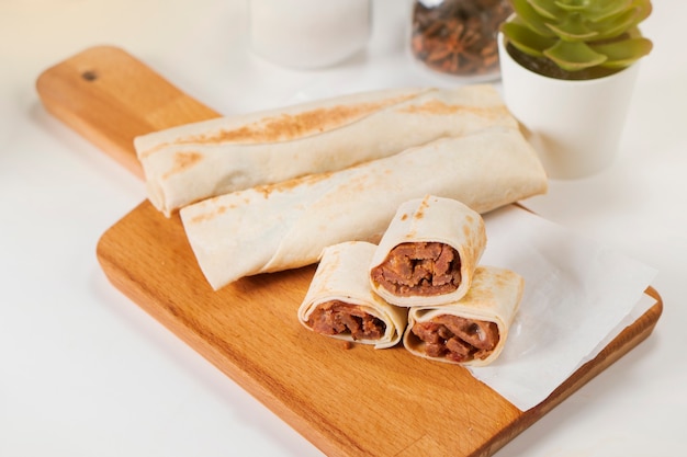 Shawarma with meat and mayonnaise on a wooden cutting board