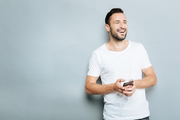 She answered me. Attractive man using phone while looking aside and standing over grey background