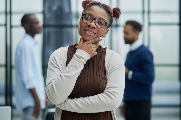 She is standing in a modern office with her colleagues in the background