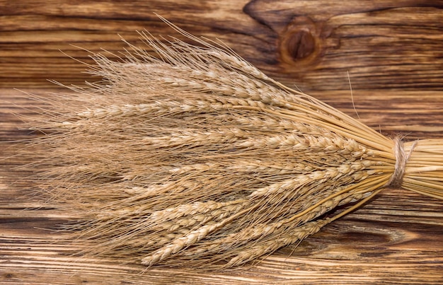 Sheaf of ears of wheat on wooden background