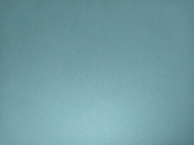 Photo a sheet of paper or thin cardboard in blue lighting on the one hand light and shadow cellulose texture calm soft cold tone background