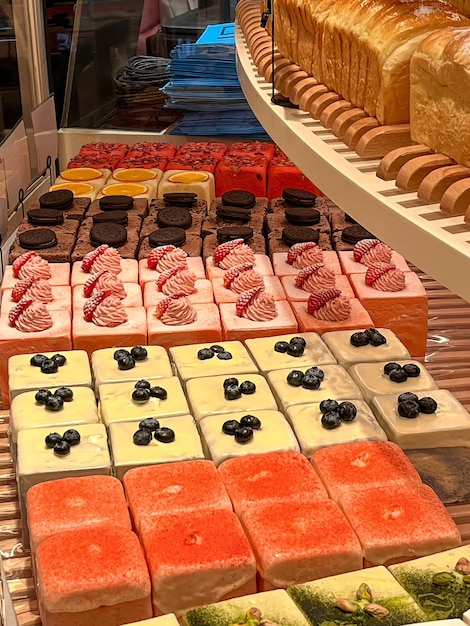 A shelf of different colored cakes with a white shelf that says " sweet ".