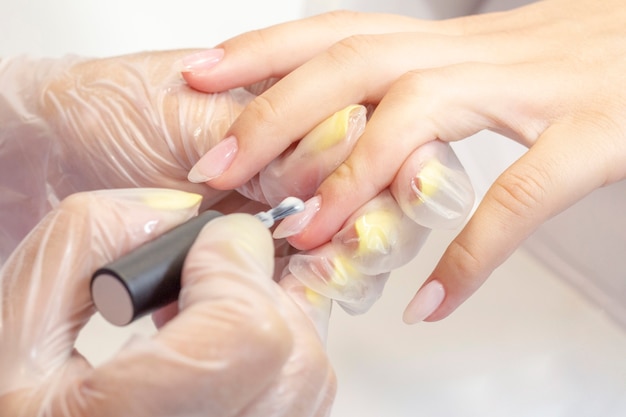 Photo shellac coating master applies nail polish to client. nude color lacquer