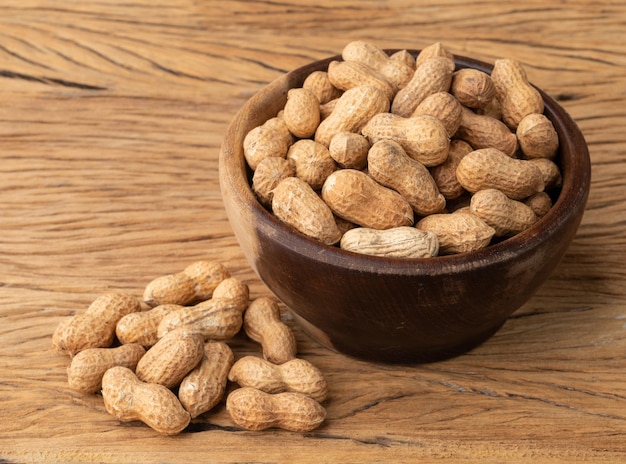 Shelled peanuts on a bowl over wooden table.