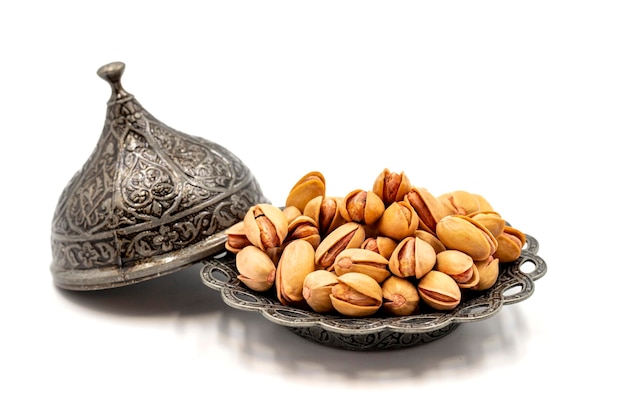 Shelled pistachios isolated on a white background Pistachios on a rustic serving plate