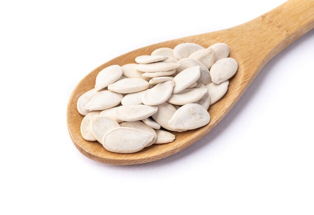 Shelled pumpkin seeds in a spoon isolated over white background