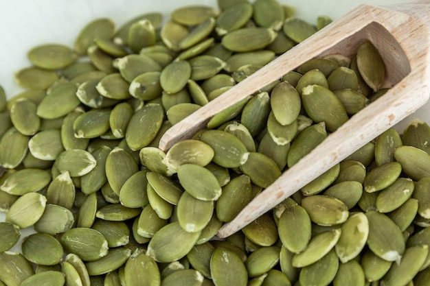 Shelled pumpkin seeds with a wooden scoop Health and natural products Closeup