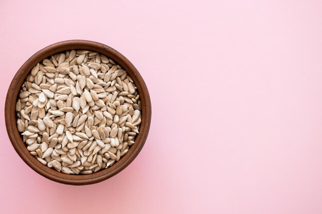 Shelled sunflower seeds over pink background