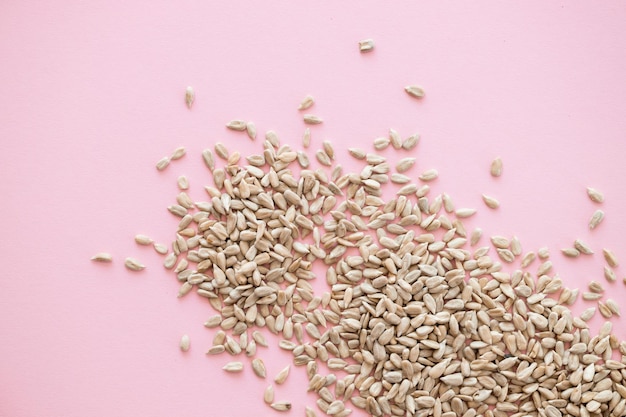 Shelled sunflower seeds over pink background