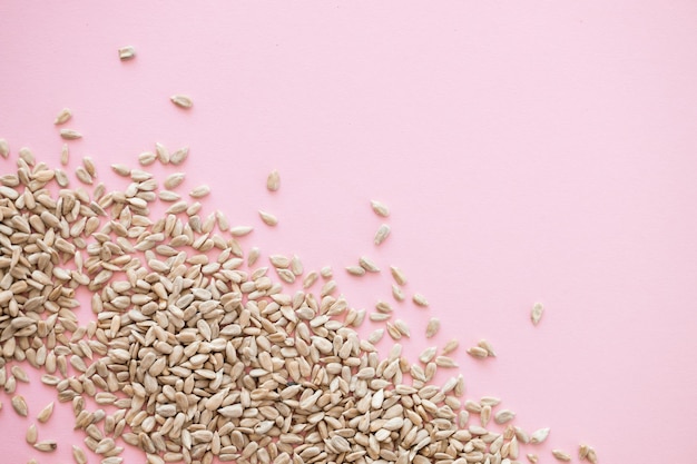 Shelled sunflower seeds over pink background