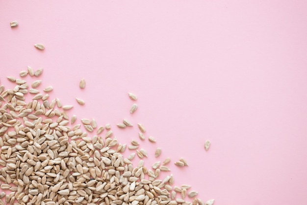 Shelled sunflower seeds over pink background