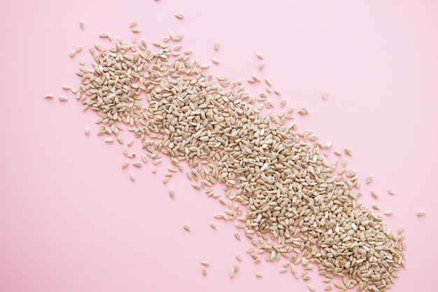 Shelled sunflower seeds over pink background