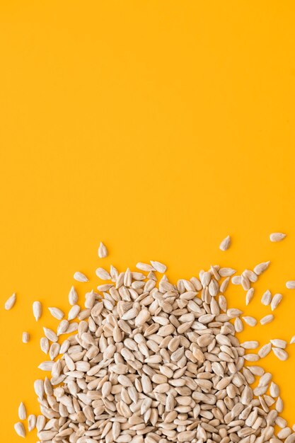 Shelled sunflower seeds over yellow background