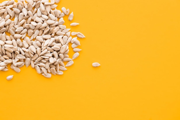 Shelled sunflower seeds over yellow background