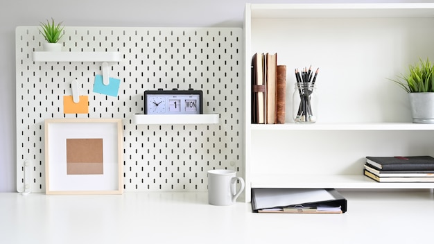 Photo shelves and pegboard with office supply on workspace table 