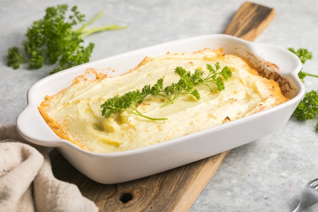 Shepherd's Pie with ground beef, potato and cheese on wooden background, top view, copy space. Traditional homemade Irish casserole