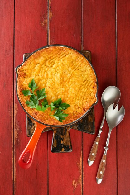 Shepherds Pie with ground beef peas carrots onions potato and cheese on old wooden background in cast iron pan Traditional British dish homemade casserole minced meatTop view Copy space