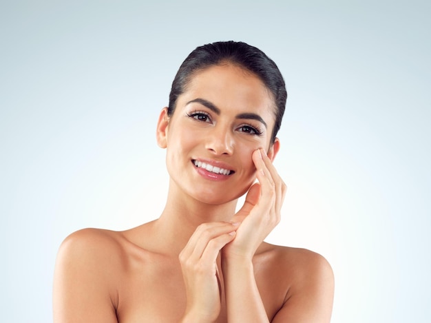 Shes been gifted with a gorgeous glowy complexion Studio shot of an beautiful young woman feeling her skin against a gray background