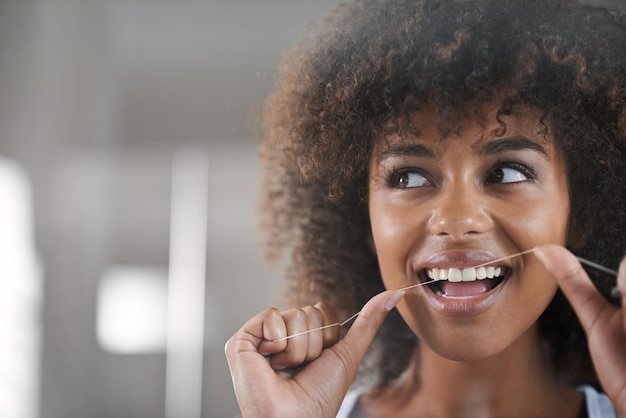 Shes big on dental hygiene shot of a young woman flossing her teeth in the mirror