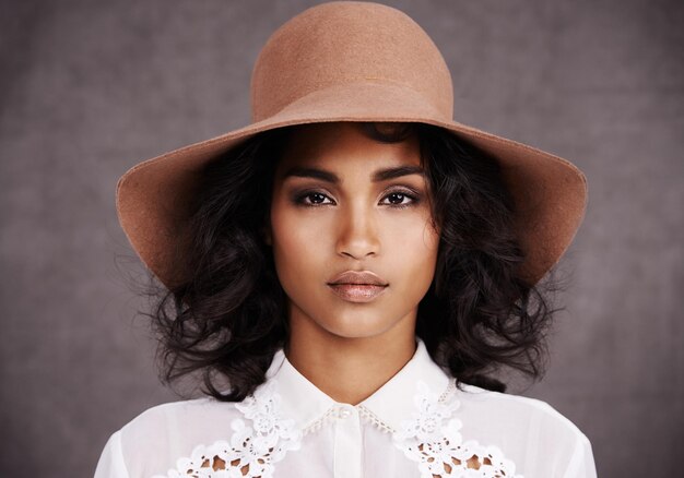 Shes not driving Miss Daisy Cropped portrait of a stylish young woman wearing a hat standing against a gray background