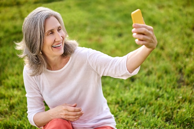 Shining adult woman with smartphone in outstretched hand