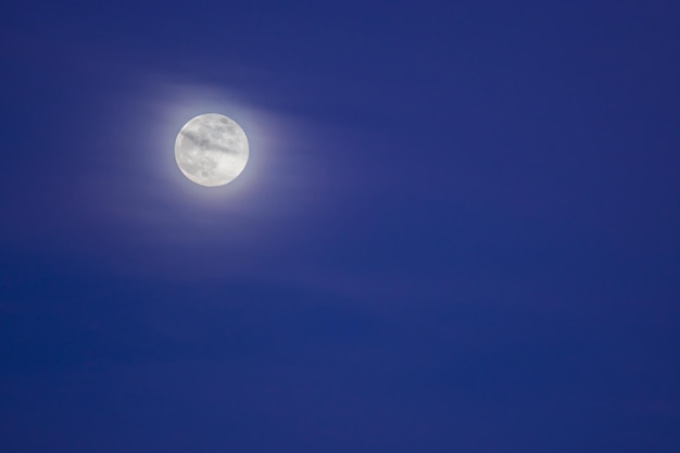 Shining moon with soft clouds on the sky during blue hour left side