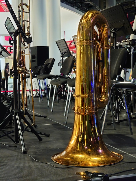 Photo shiny brass trombone standing on a stage floor with a backdrop of the equipment of the band in a low angle floor level view