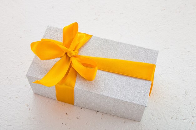 Shiny gift box with a gold bow on a white background