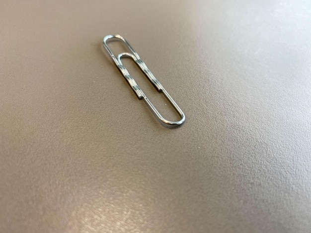 Shiny metal paper clips on a desktop with stationery in a business office Close view