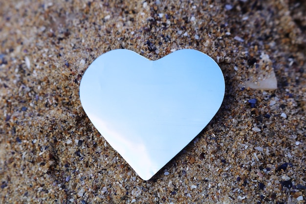 Shiny paper heart on the sand