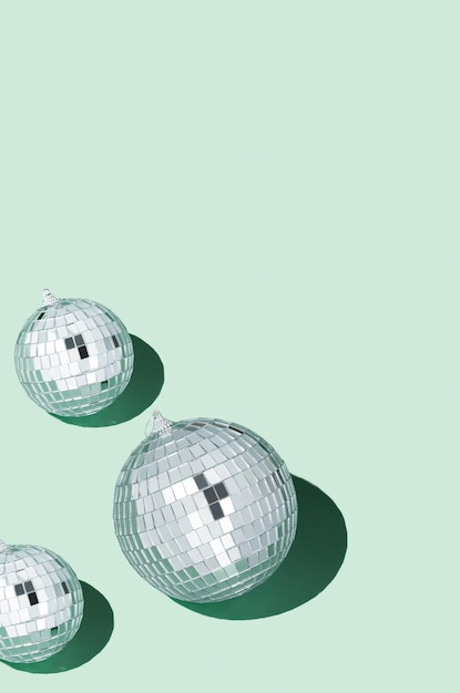 Shiny silver disco balls over green background Creative Christmas pattern 90s retro party time concept Xmas holiday background Top view Flat lay Copy space