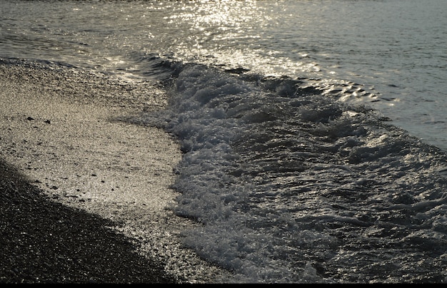 Shiny silver water on the sea pebble beach