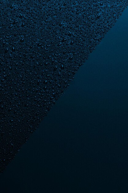 Shiny water falls on the black surface blue background drops of water on black drops of water on a black glass surface Texture View from above