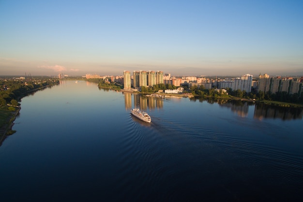 The ship is on the river at sunset. he slowly floats along the river in the rays of the setting sun