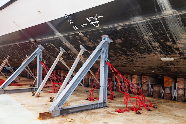 The ship's hull is dry docked on wooden blocks and supported by metal piers