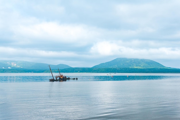 Shipwreck against the backdrop of a sea bay with foggy mountains in the background