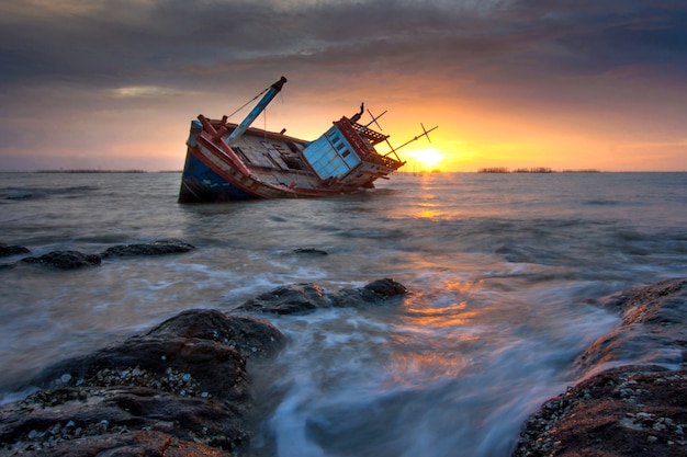 A shipwreck moored by the sea during sunset