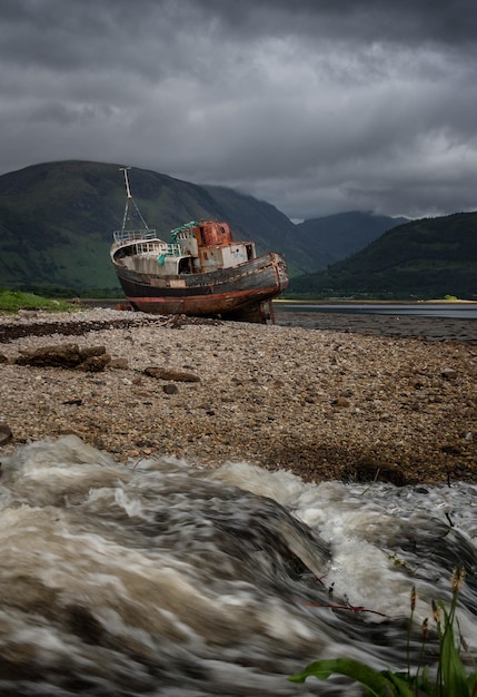 Shipwreck near Fort William with running water in the foreground and clouds above Ben Nevis Scotland