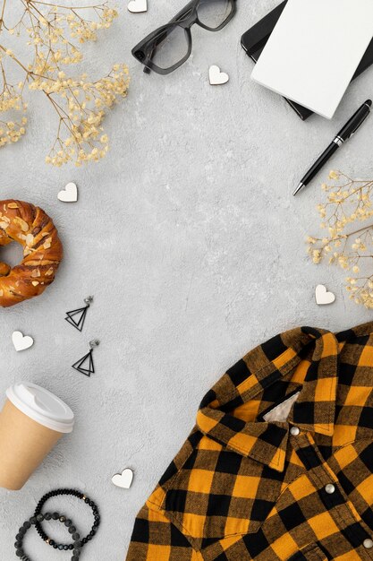 Shirt, coffee cup, donut, glasses, pen and more objects in frame shape on concrete background