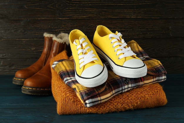 Shirt, sweater, sneakers and boots on wooden table.