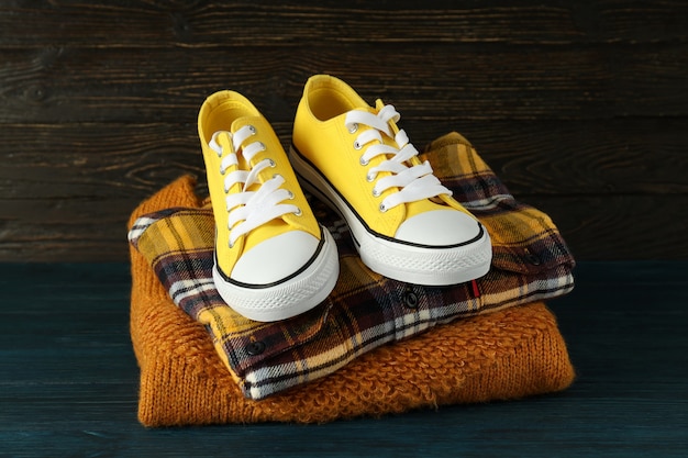 Shirt, sweater and sneakers on wooden table.