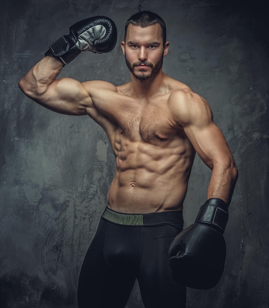 Shirtless aggressive fighter with burning boxer gloves on grey background.